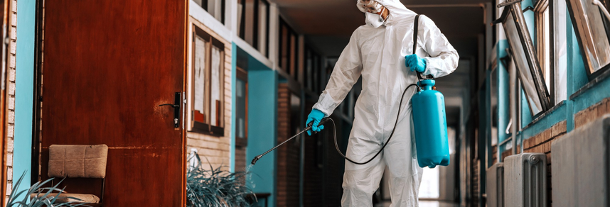 Pest control worker spraying inside commercial hallway – PC Los Angeles