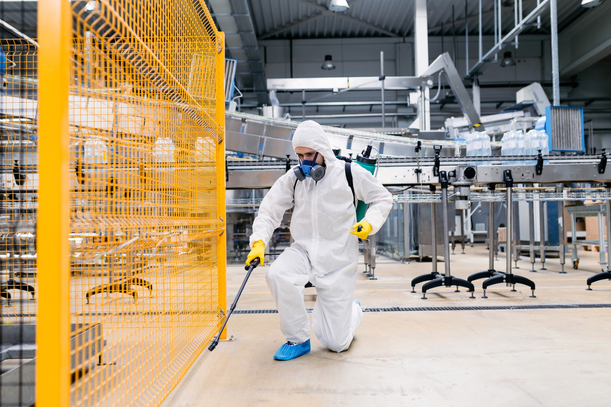Pest control technician spraying inside industrial facility – PC Los Angeles