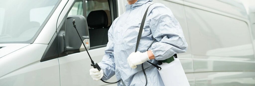 Pest control technician holding sprayer near service van – PC Los Angeles