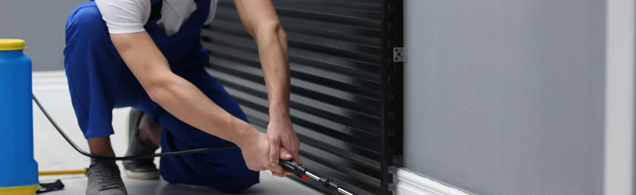 Pest control technician spraying along wall base – PC Los Angeles